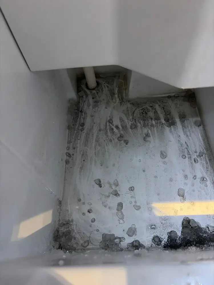 GE undercounter ice machine reservoir corner with scale and black buildup before cleaning, Park City, Utah.
